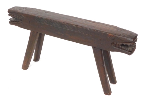 An African wooden two seated stool, the seat carved as a double headed crocodile, 98cm wide.