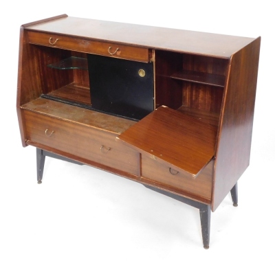 A G-Plan 1950's teak sideboard, with a single drawer above two ebonised sliding doors enclosing a drinks cabinet, flanked by a dropped down cabinet, over one long and one short drawer, raised on ebonised legs, brass capped, 76cm high, 121cm wide, 48cm dee