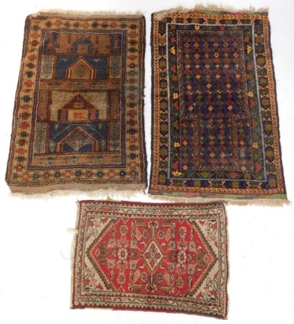 A group of Persian rugs, to include a prayer rug with a geometric design in electric blue within multiple borders, another prayer rug decorated with buildings, geometric devices, etc, and a red ground mat, with multiple borders, 91cm x 63cm, 143cm x 83cm