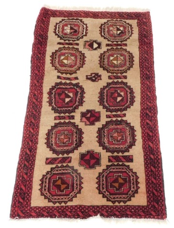 A Persian Belouch type rug, with a design of two rows and five medallions in red, on a cream ground with three narrow borders, 155cm x 90cm.