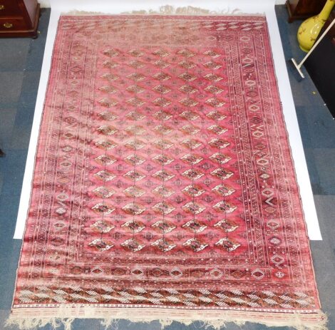 A Belouch type rug, silk effect, with a design of medallions on a red ground with one wide and four narrow borders, 342cm x 245cm.