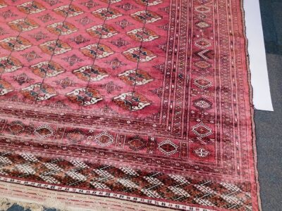 A Belouch type rug, silk effect, with a design of medallions on a red ground with one wide and four narrow borders, 342cm x 245cm. - 2