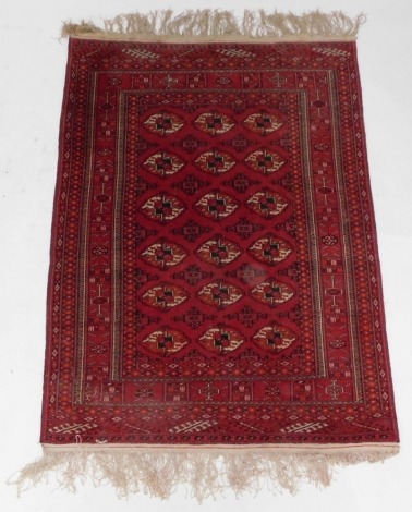 An Afghan Belouch rug, with three rows of medallions on a red ground, within multiple borders, 106cm x 174cm.