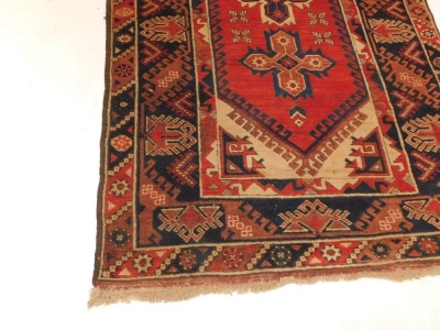 A Persian rug, decorated with three star shaped medallions on a red ground, with cream spandrels and one wide and two narrow borders, 120cm x 210cm. - 2