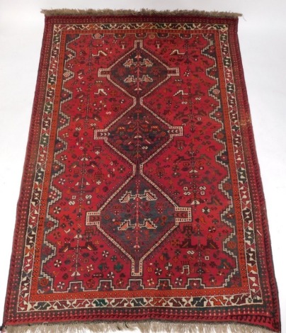 A Persian rug, with a central pole medallion in black on a red ground with multiple borders, 264cm x 169cm.