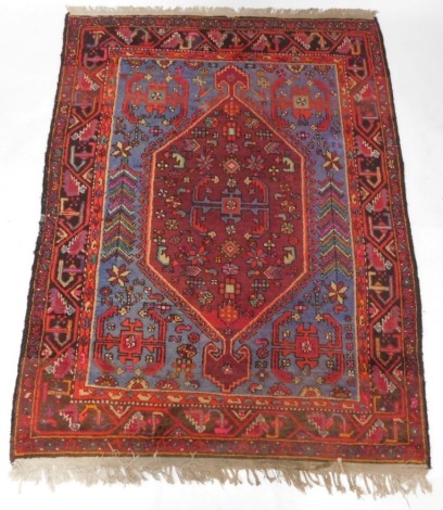A Persian rug, with a central large pole medallion in deep red, on a blue ground with multiple borders, 213cm x 152cm.