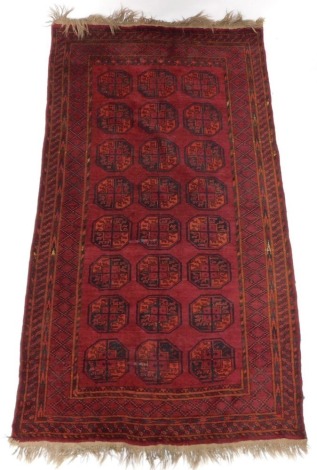 A Belouch rug, with three rows of medallions, on a red ground, with multiple borders, 124cm x 244cm.