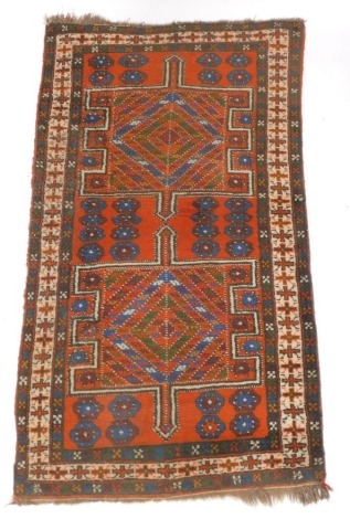 A Persian rug, with two geometric multi coloured compartments, on an orange ground with multiple borders, 114cm x 205cm.