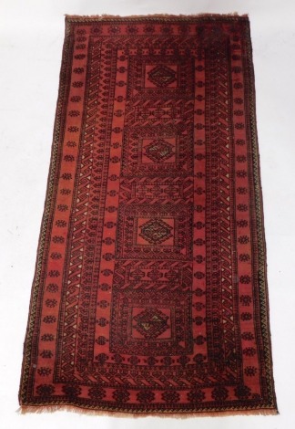 A Persian rug, with a design of latch hook medallions, each in a rectangular compartments within multiple borders, 222cm x 114cm.