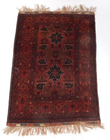 A Persian rug, with two star shaped medallions in navy on a deep orange ground, with multiple borders, 177cm x 102cm.