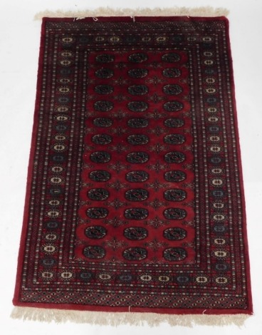 An Afghan Belouch rug, with three rows of medallions in blue, on a red ground with multiple border, 198cm x 122cm.