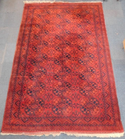 A Belouch type rug, with a design of medallions on a deep orange ground with multiple borders, 326cm x 206cm.