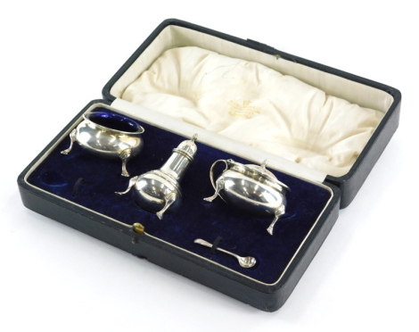 A George V silver condiment set, comprising pepper pot of baluster form, 9cm high, open salt and mustard pot, Birmingham 1922, with associated spoon, 5.2oz, (cased).