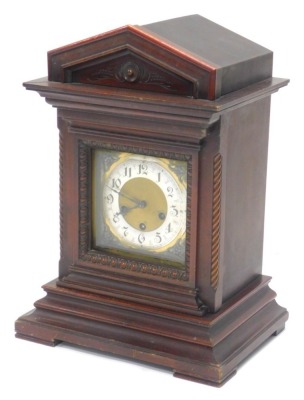 A late 19th/early 20thC German mantel clock, in a carved walnut case with brass dial and silvered chapter ring, stamped Germany, 47cm high.