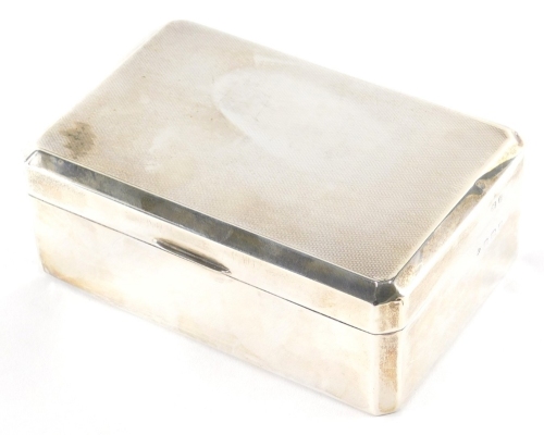 A George VI silver cigarette box, with engine turned canted top, thumb mould handle and cedar lined interior, Birmingham 1937, 7cm high, 14cm wide, 9cm deep, 13½oz all in.