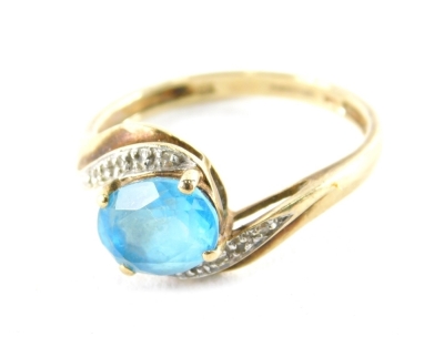 A 9ct gold blue topaz and cz set twist ring, the central blue topaz in four claw setting, with white gold scroll design shoulders, on a yellow metal band, stamped 9K, ring size T, 3g all in.