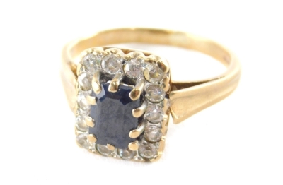 A 9ct gold sapphire and cz cluster ring, the rectangular cluster with central rectangular cut sapphire in claw setting, surrounded by fourteen cz stones, ring size M½, 3.9g all in.