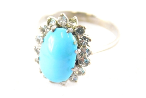 A turquoise cluster dress ring, the turquoise in claw setting surrounded by imitation diamonds in raised basket setting on a gold coloured band, stamped 18kt, ring size N½, boxed.