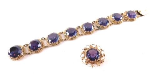 A Victorian/Edwardian style bracelet and brooch set, comprising a bracelet set with purple paste stones, in yellow metal rose gold coloured setting, unmarked 20cm long, together with a similar brooch, with single pin back, unmarked, 2.5cm wide, 61g all in