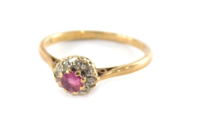 A 9ct gold garnet and diamond cluster ring, the round brilliant cut raised garnet in a eight claw settings, surrounded by illusion set tiny diamonds in white gold on a raised basket, with pierced design shoulders, on a yellow metal band, ring size R½, 2.1