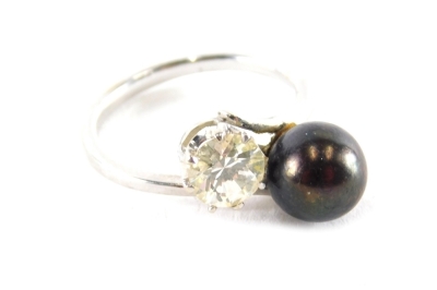 A modern dress ring, set with black and cultured pearl, and paste white stone, with twist design central panel, on white metal band, unmarked, ring size M½, boxed.