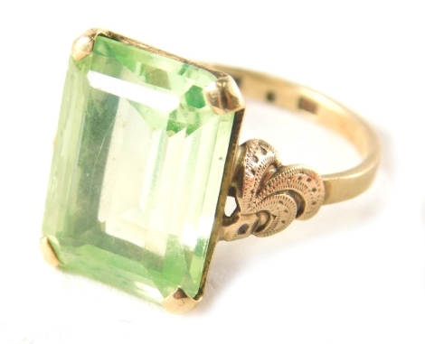 A 9ct gold dress ring, the rectangular faceted peridot, in full coloured setting, with fleur de lys panelled shoulders, ring size T½, 5.4g all in.