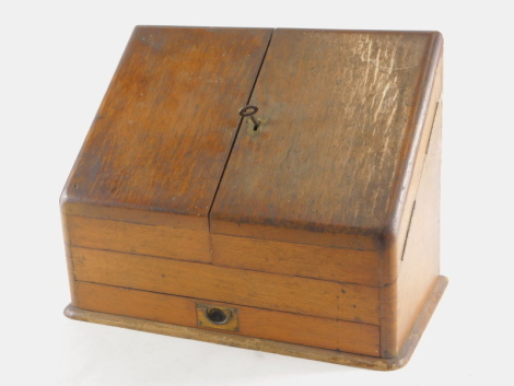 An early 20thC oak stationery cabinet, with sloping front, fitted interior and front drawer, with key, 32cm high, 39cm wide, 21cm deep.