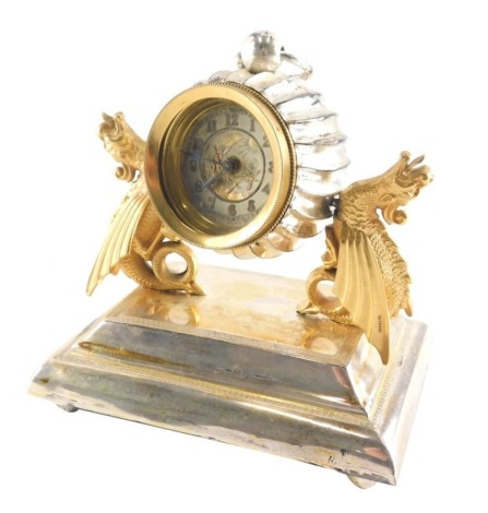 A travel clock, on silver plated stand, with an articulated and adjustable pocket watch centre with 5cm diameter dial, held by serpents, partial label beneath.