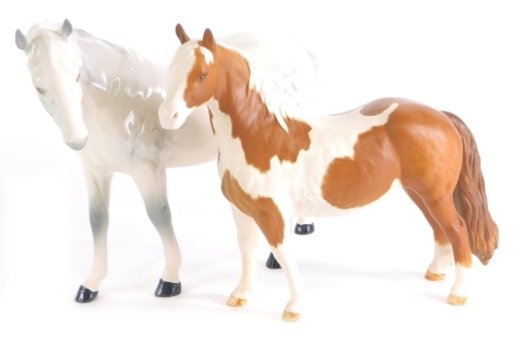 A Beswick palomino horse, 17cm high, matt and a dapple white horse, head lowered, printed marks beneath. (2)