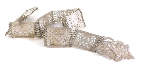 A highly elaborate Middle Eastern belt, set with rectangular pierced sections, broken by chains, with an elaborate floral and star buckle, unmarked, 75cm long.