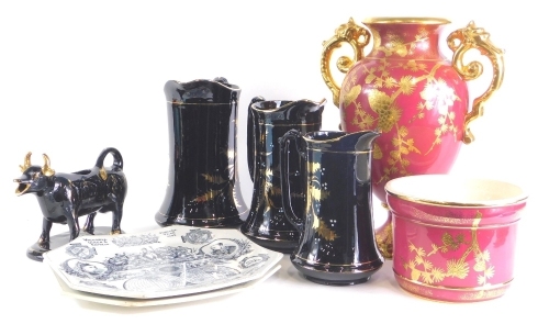 A collection of 19thC and later ceramics, to include a black glazed cow creamer, graduated set of three black glazed jugs, a two handled urn and stand, decorated with acorns on a red ground, and a pair of Queen Victoria 1887 Jubilee plates.