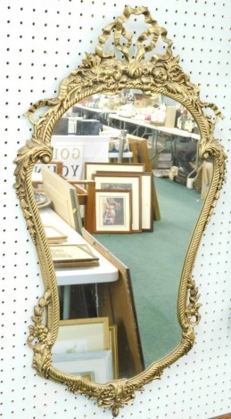 A gilt gesso cartouche shaped wall mirror, decorated with ribbons, flowers, leaves, etc., 107cm x 50cm.