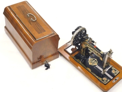 A Frister and Rossmann sewing machine, decorated in black and gilt in figured walnut carrying case, 52cm x 42cm wide.