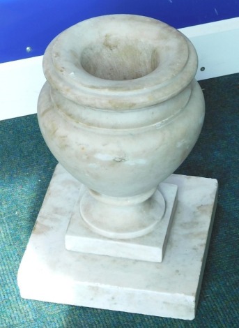 A baluster shaped marble floor urn, on a square plinth, 36cm high.