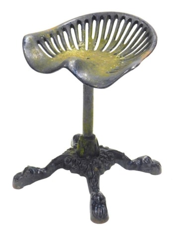 A cast iron tractor seat stool, on a shaped stem, and scroll feet, 52cm high.
