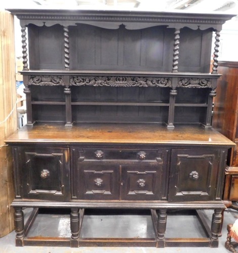 A late 19th/early 20thC oak dresser, the raised back with spirally turned supports, floral carved frieze, the base with a moulded edge above a frieze drawer, above two further panelled doors, flanked by two larger doors on bulbous turned supports with str