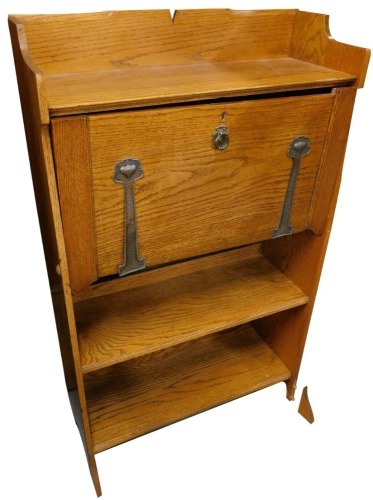 An early 20thC oak Art Nouveau student's desk or bureau, with a raised back, the fall front applied with hammered brass hinges, above two shelves, 70cm wide.