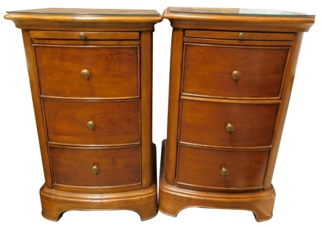 A pair of Laura Ashley hardwood bedside cabinets, each of bowfronted form, with a slide and three drawers, with turned brass handles, on bracket feet, 68cm high, 42cm wide.