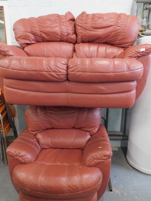 A two seater burgundy leather sofa and a matching arm chair.