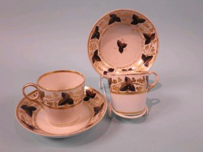 A pair of early 19thC porcelain cups and saucers each decorated in black