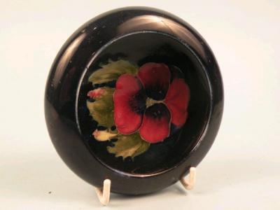A Moorcroft small bowl decorated to the inside with a pansy on a navy ground
