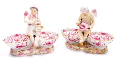 A pair of late 19thC Meissen porcelain table salts, modelled as winged putto and each with two bowls, the female figure seated with a coffee grinder and the male figure with bowl and spoon, decorated in pink and gilt on rococo bases, crossed swords mark, 