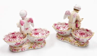 A pair of late 19thC Meissen porcelain table salts, modelled as winged putto and each with two bowls, the female figure seated with a coffee grinder and the male figure with bowl and spoon, decorated in pink and gilt on rococo bases, crossed swords mark, - 2