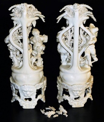 A pair of Continental white glazed biscuit figure groups on stands, each modelled with three boy figures on a naturalistic base with a tree and vine bocage, the stand moulded with repeating lion's head masks and rococo scrolls, blue crown and N mark, 38cm - 2