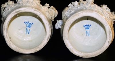 A pair of Continental white glazed biscuit figure groups on stands, each modelled with three boy figures on a naturalistic base with a tree and vine bocage, the stand moulded with repeating lion's head masks and rococo scrolls, blue crown and N mark, 38cm - 3