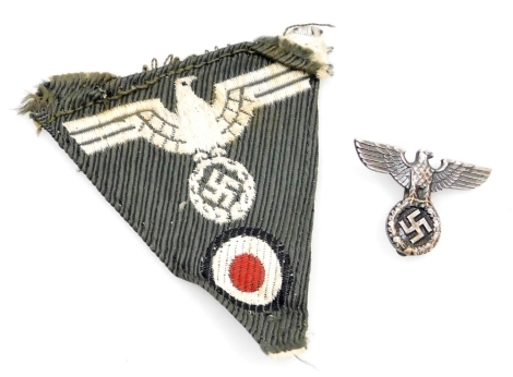 A German Third Reich eagle pin badge, the reverse marked RM M1, and a Luftwaffe triangular cloth insignia badge. (2)