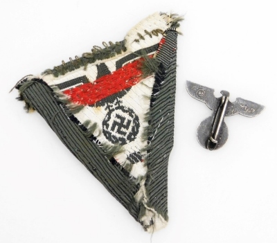 A German Third Reich eagle pin badge, the reverse marked RM M1, and a Luftwaffe triangular cloth insignia badge. (2) - 2