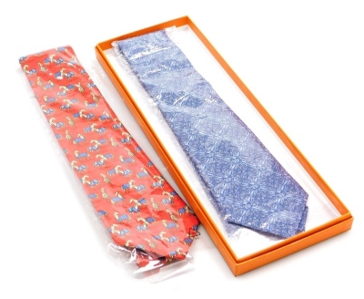 Two Hermes silk ties, comprising a blue tie with sunflower design, and a red tie decorated with horses, one boxed.