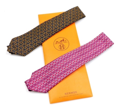 Two Hermes silk ties, comprising a burgundy coloured tie with golf club and balls design, and a blue tie with chain link design, contained in a Hermes sleeve case.