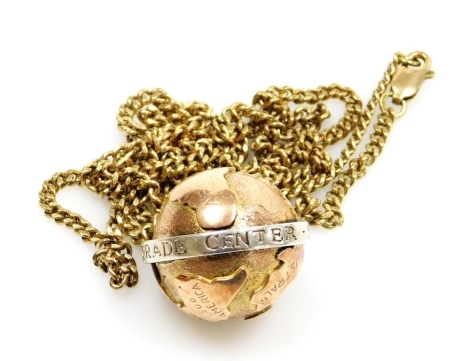 A 9ct gold World Trade Centre pendant, the 9ct globe with applied white metal band stamped World Trade Centre 9.11.01.1973, with a yellow metal curb link chain stamped 375, the pendant 2.5cm high, the chain 64cm long overall, 20.7g all in.